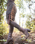 Rugged unbranded brown leather lace-up mid-calf boots with wraparound laces, photographed outdoors in soft light