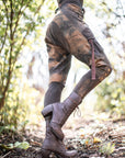 Rugged brown leather lace-up boots with thick soles and laced ankle design outdoors in sunlit woods