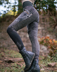 Rugged black suede riding boots with side zipper and quilted texture, standing on outdoor garden ground