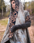 Geometric embroidered hooded shawl in grey wool with navy and tan trim, worn outdoors in soft daylight