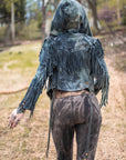 Fringed hooded denim jacket in dark blue with long fringe detailing, worn outdoors in soft daylight