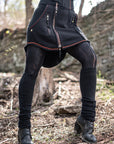 Front-zipped utility jacket in black fabric with red piping and multiple zippers outdoors