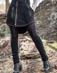 Utility skirt black denim with front zippers, pockets, and orange trim on an outdoor stone path