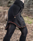 Black hooded jacket with orange-red trim, textured fabric and drawstring on an outdoor rocky setting