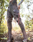 Rugged brown leather lace-up boots with eyelets and visible laces, worn outdoors on a forest path