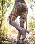 Unbranded casual pants in brown with cargo-style pocket seams, worn outdoors in golden-hour light