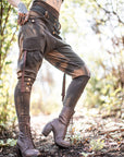 Lace-up unbranded leather boots in dark brown with tall shaft and buckled straps, set on woodland path