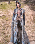 Bohemian hooded cloak in light gray suede with dark patterned trim, draped outdoor portrait