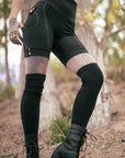 Sleek black pants with contrast gold side piping and snap cuff details in outdoor field